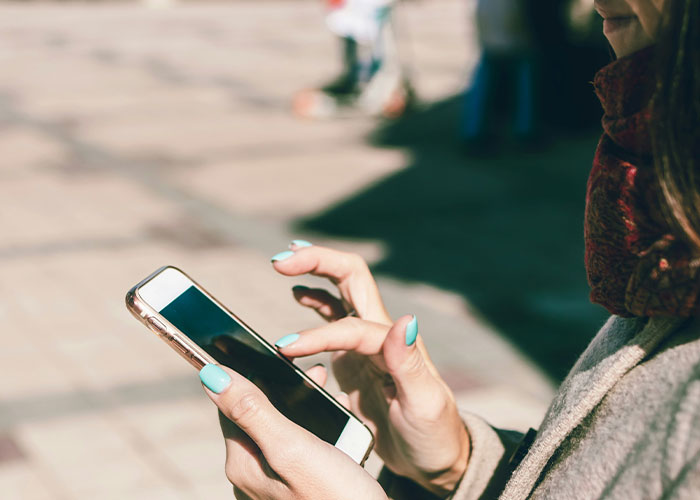 Person outdoors using a smartphone, possibly tracking steps, focusing on a healthy lifestyle and reaching 10K steps daily.