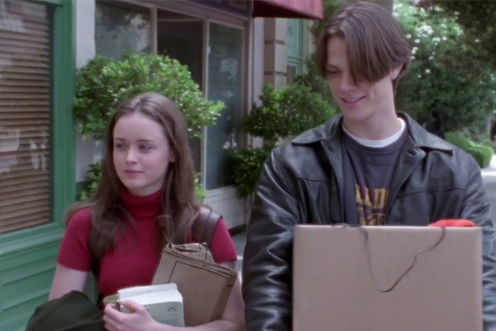 A young couple walking outdoors, each holding books, representing a TV couple with little chemistry.