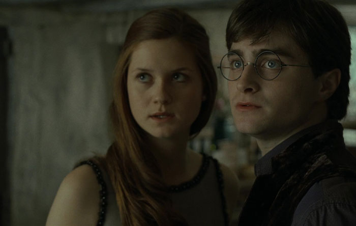 TV couple with less chemistry in a dimly lit room, looking towards something unseen.