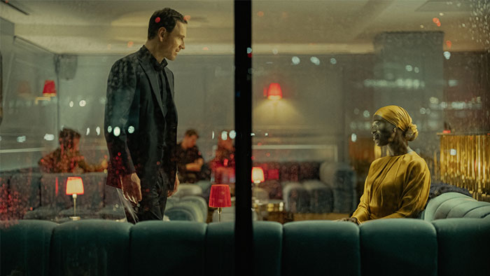 A man and woman in a dimly lit lounge, separated by glass, depicting a lack of chemistry.