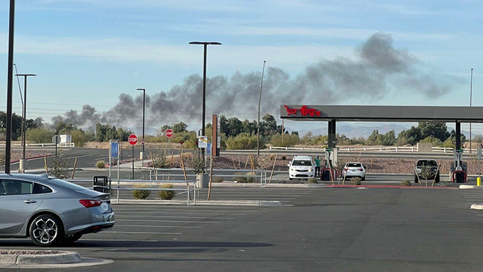 Smoke rising in the distance after two planes collide mid-air in Arizona, as seen from a parking lot.