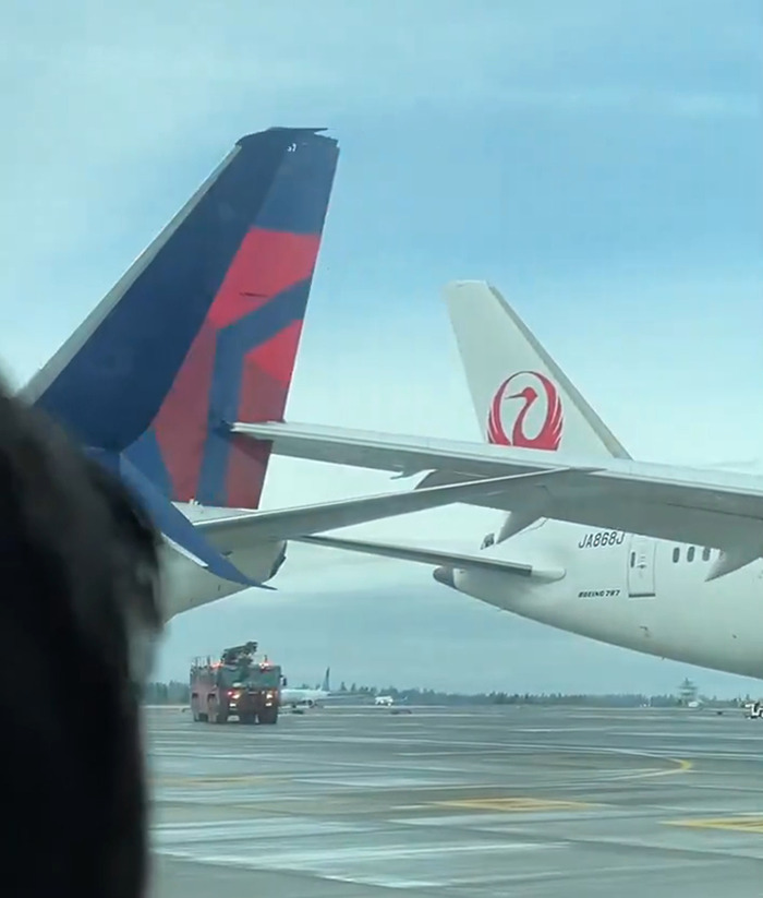 Two planes collide at Seattle airport, tails touching on the runway, against a cloudy sky. Two planes collide at Seattle airport, tails touching on the runway, against a cloudy sky.