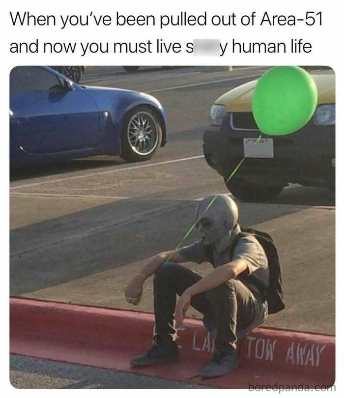 Alien with a green balloon sitting on a curb, humorously depicting a random meme scenario.