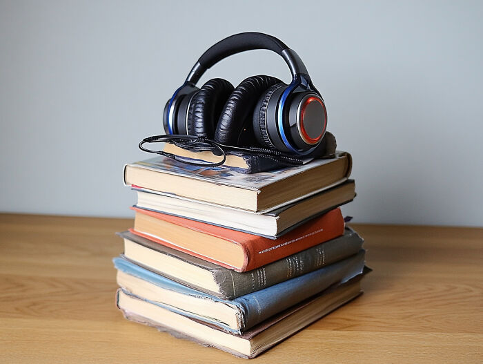 Headphones resting on a stack of books, symbolizing an unpopular opinion poll on audiobooks versus traditional reading.