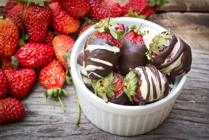 Valentine's gifts for kids: chocolate-covered strawberries in a bowl on a wooden table.