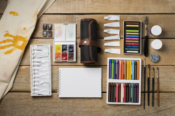 Art supplies for kids on Valentine's Day, including paints, brushes, colored pencils, and a blank notepad.