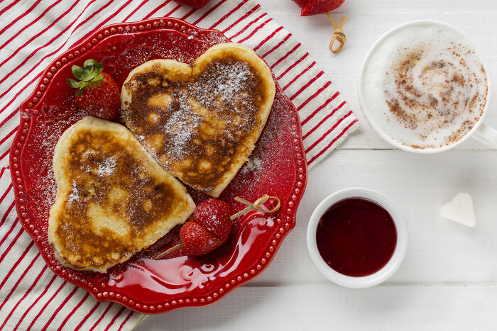 Heart-shaped pancakes with strawberries and a cup of cocoa, perfect Valentine's gift idea for kids.