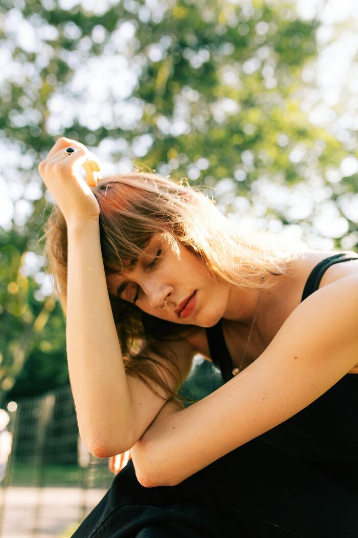 Guest appearing tired at a wedding, sunlight streaming through trees.