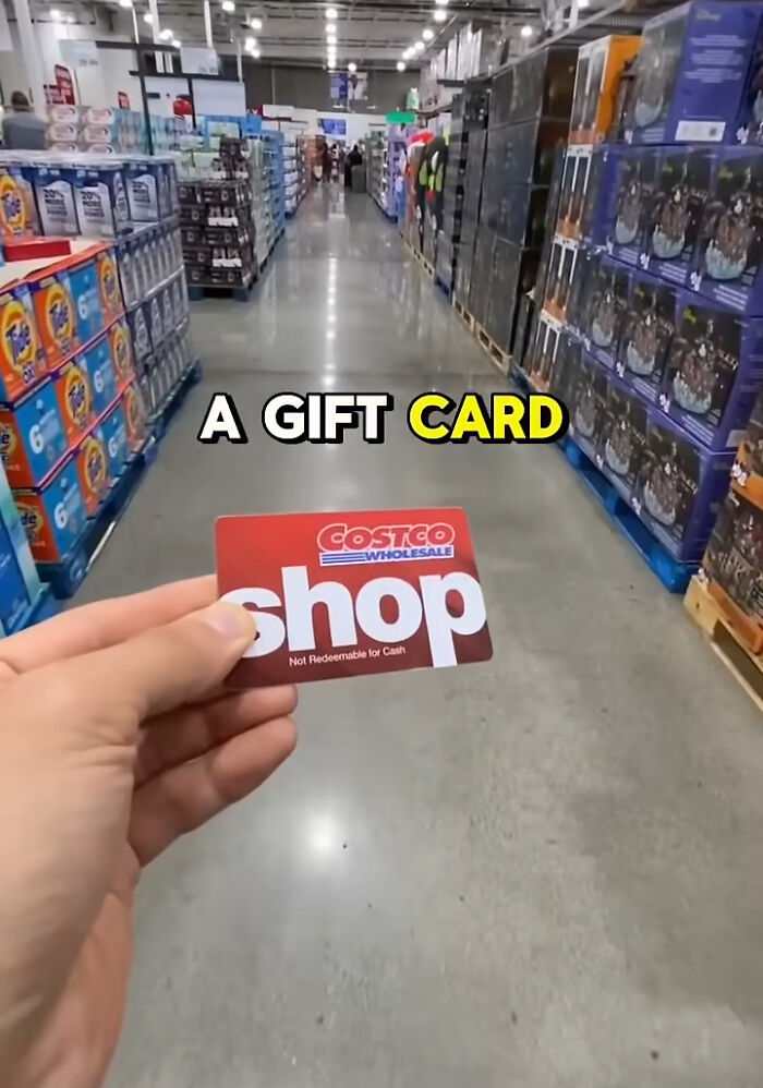 Hand holding a Costco gift card inside a store aisle, representing shopping hacks.
