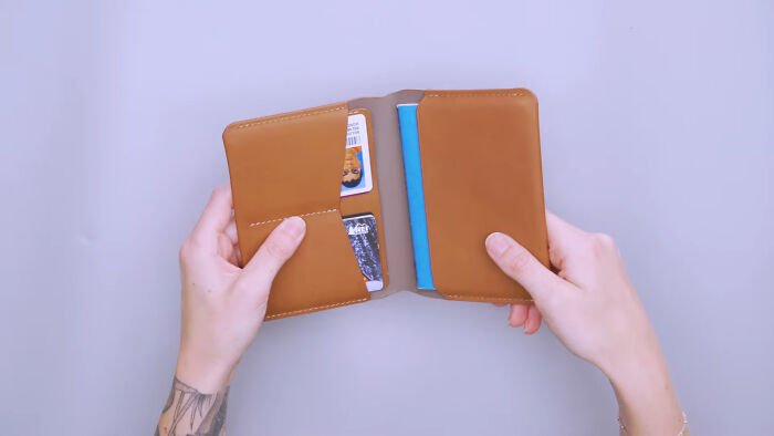 Hands holding a brown travel wallet, showcasing organized essentials for easier and more peaceful travel.