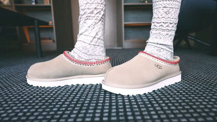 Cozy slippers with patterned socks on a carpet, representing recent fashion trends people hate.