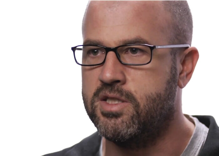 Man with glasses and a beard discussing pop culture moments, set against a white background.