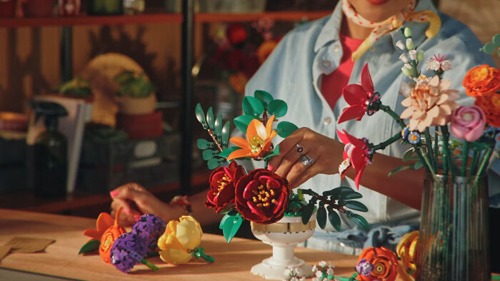 Person arranging colorful, durable flower decor on a table, demonstrating beautifully designed items for longevity.
