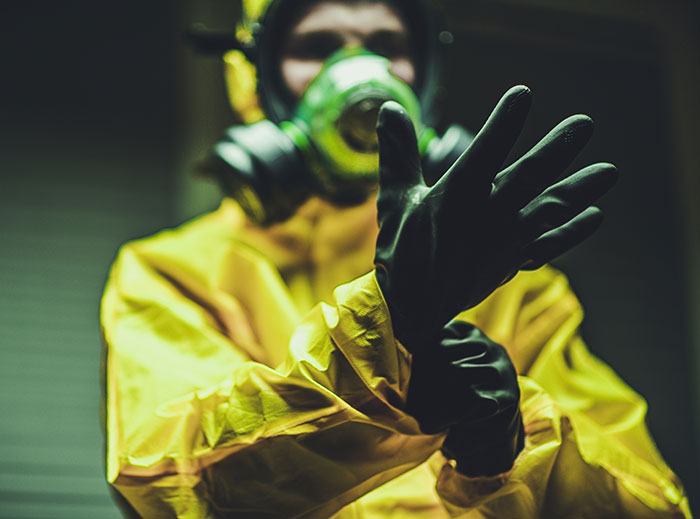 Person in hazmat suit adjusting gloves, related to unknown illness response. Person in hazmat suit adjusting gloves, related to unknown illness response.