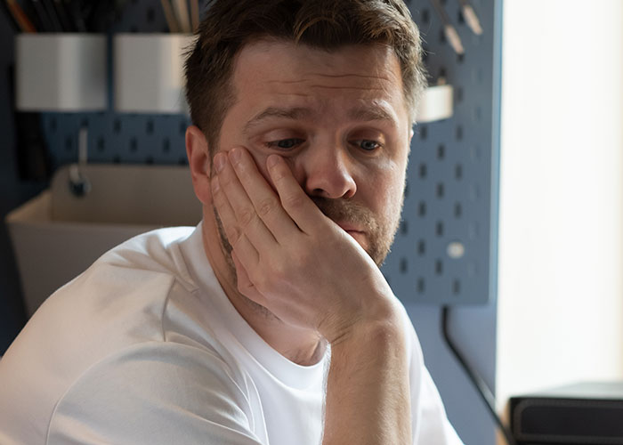 Man in a white shirt looks concerned, resting his face on his hand, related to a server's missing $2,500 tip. Man in a white shirt looks concerned, resting his face on his hand, related to a server's missing $2,500 tip.