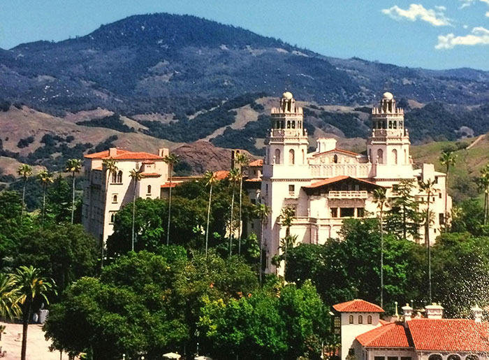 Luxurious mansion nestled in lush greenery with mountain backdrop, showcasing opulence of the super rich.