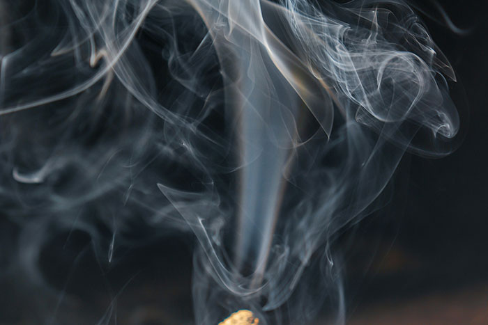 Ethereal smoke swirls against a dark background, representing the extravagant purchases of the super rich.