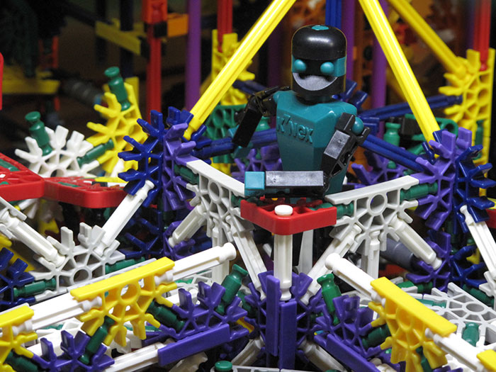 Toy robot built with K'NEX parts, representing things the super rich can buy, amidst colorful construction pieces.