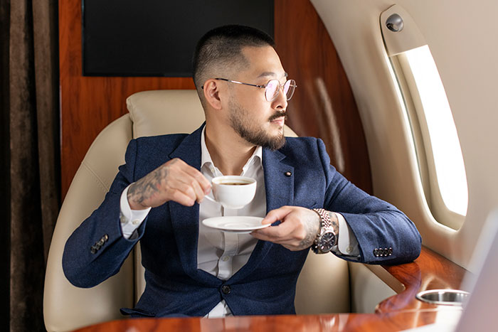 Man drinking coffee in a private jet, representing luxury purchases of the super rich.