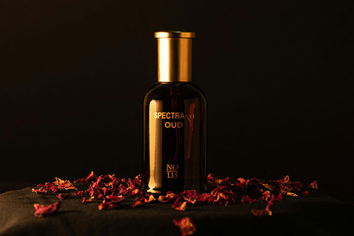 Luxury perfume bottle with a gold cap surrounded by dried rose petals, symbolizing opulent purchases of the super rich.