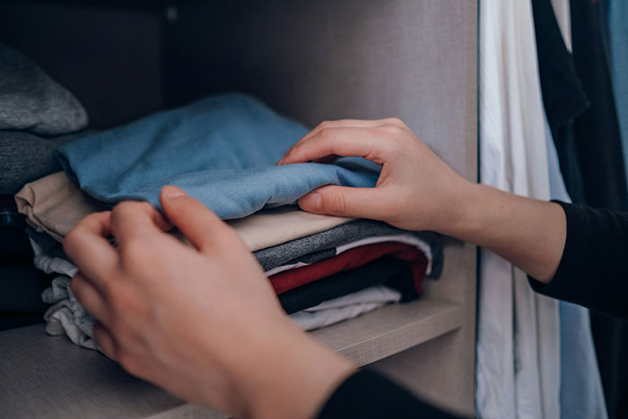 Hands organizing clothes in a closet, related to weaponized incompetence theme.