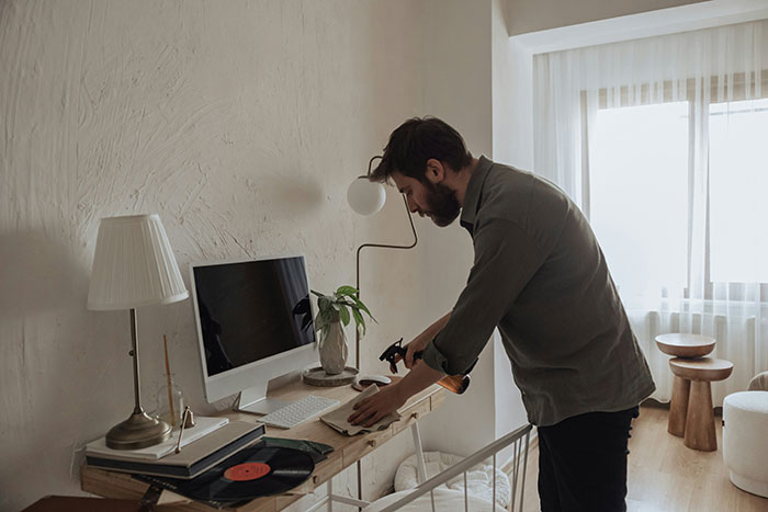 Man organizing a cluttered desk, potentially illustrating weaponized incompetence in household tasks.
