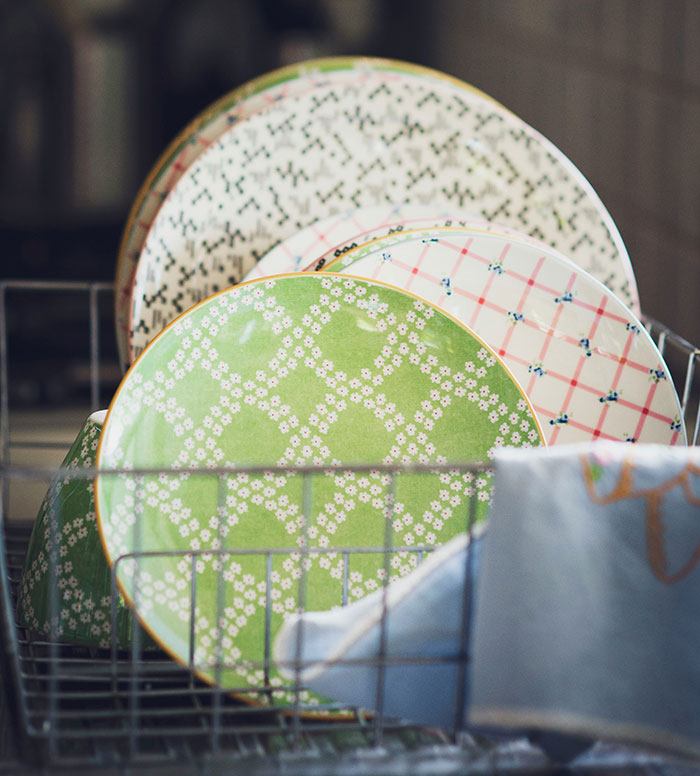 Decorative plates stacked in a dish rack, illustrating weaponized incompetence in household chores.