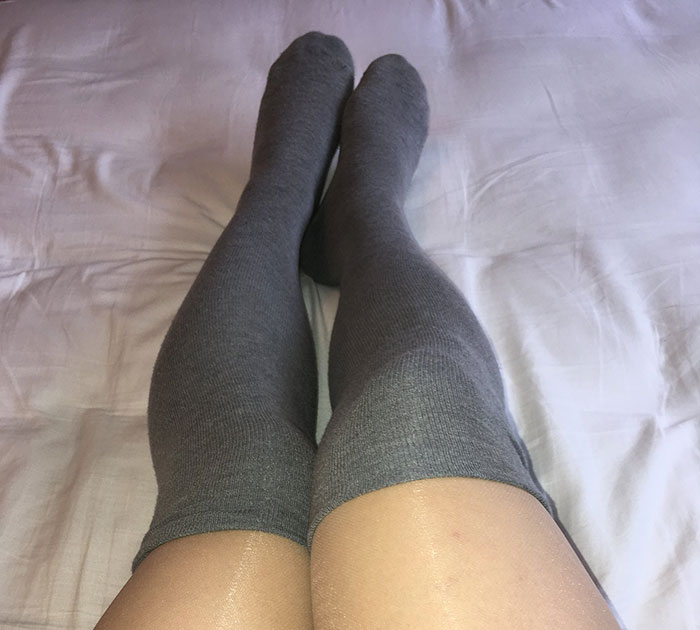 Gray knee-high socks on a bed, showcasing a cozy gift idea for men on Valentine's Day.
