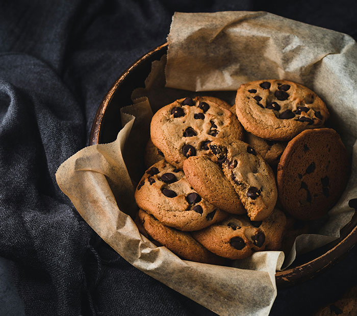 A basket of chocolate chip cookies on parchment paper, a gift idea for men on Valentine's Day.