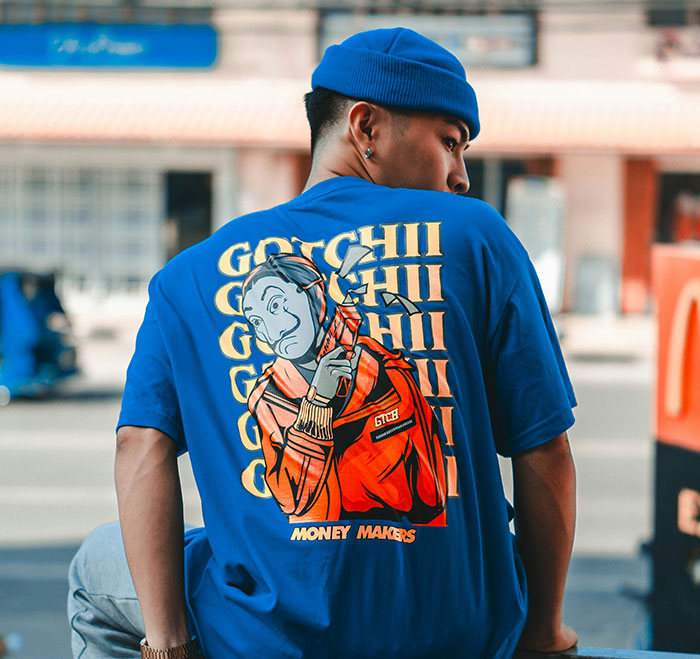 Man in blue T-shirt and beanie with artistic design, representing guys appreciating pretty things in fashion.