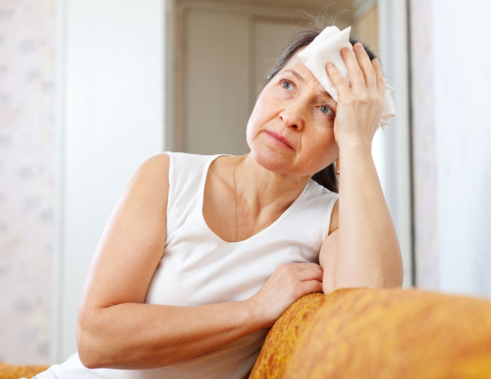 Woman looking upset, holding a cloth to her forehead, expressing emotions related to labor and newborn concerns.