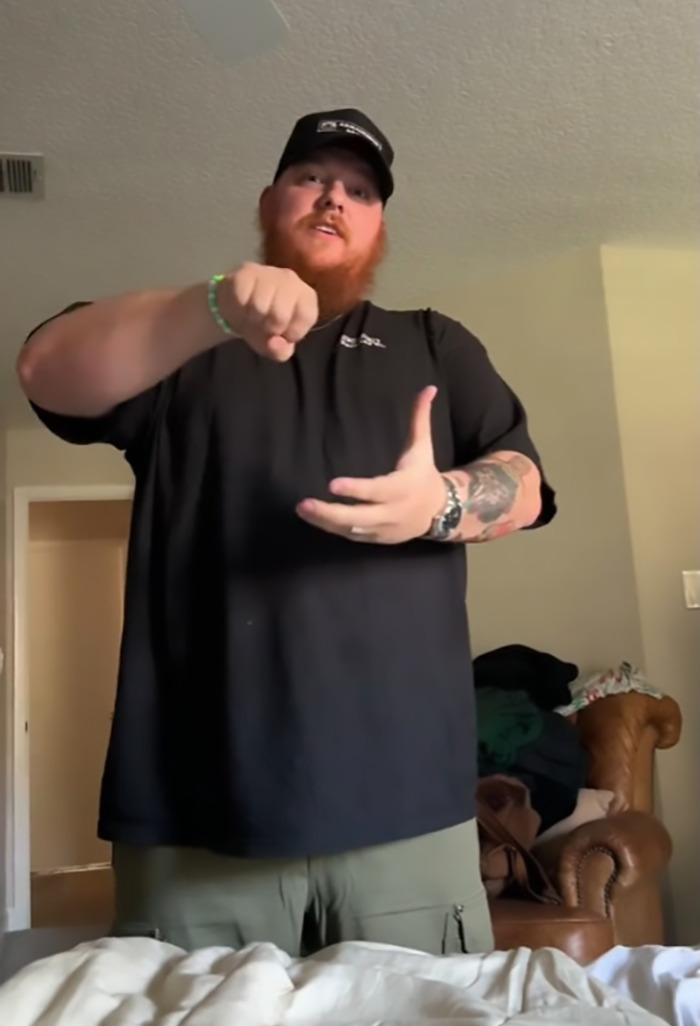 Man demonstrating a shower routine in a viral clip, wearing a black shirt and cap.