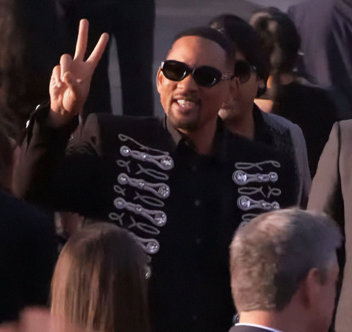 Man in sunglasses and a decorative jacket giving a peace sign at an event, associated with Will Smith and Quincy Jones tribute. Man in sunglasses and a decorative jacket giving a peace sign at an event, associated with Will Smith and Quincy Jones tribute.