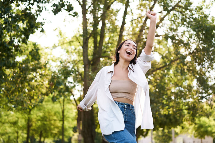 A woman joyfully running outdoors, embodying life's priceless lessons amid a lush green background.