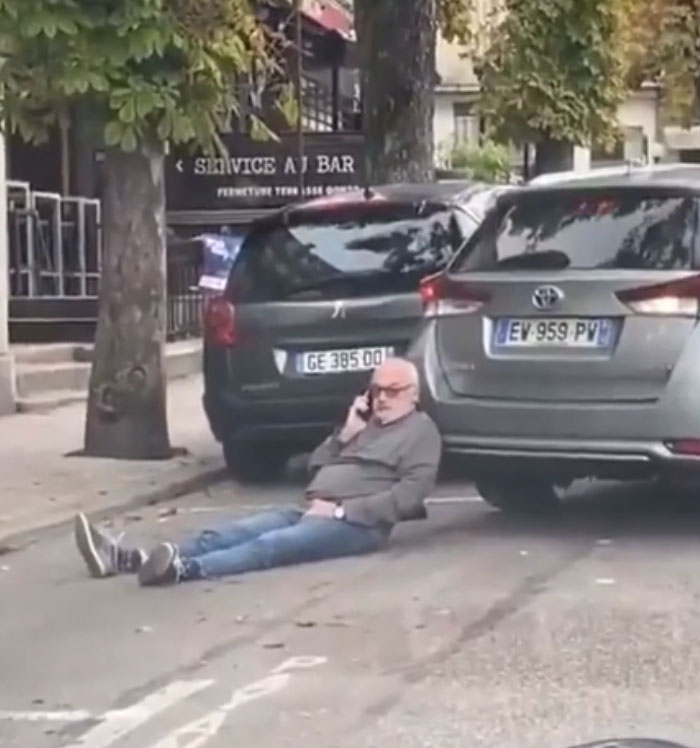 Hombre prepotente en la calle, hablando por teléfono, bloqueando autos con actitud despreocupada.