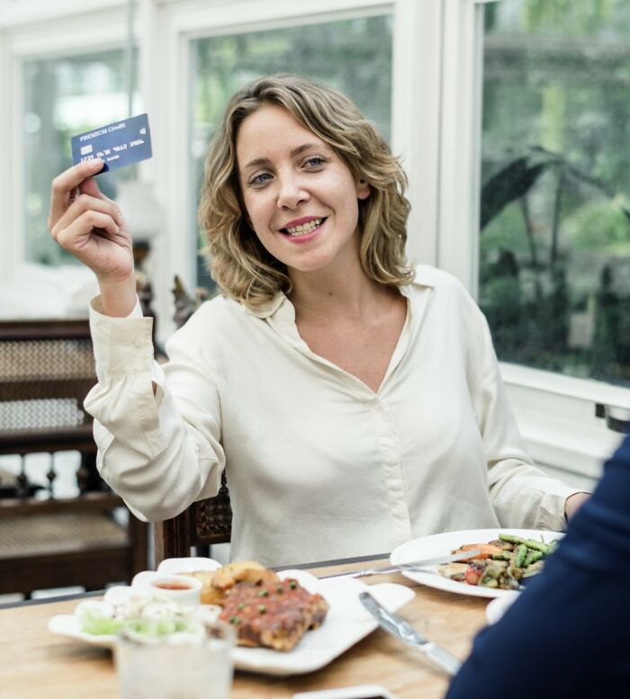 Woman holding a credit card at a restaurant, showcasing American norms.