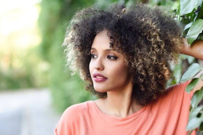 A person with curly hair in an outdoor setting, highlighting genetic blessings and natural beauty.