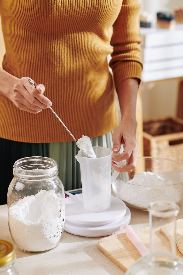 Person measuring flour on a kitchen scale, focusing on overlooked ingredients.