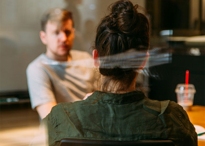 Man and woman in discussion at a table, blurred background, focus on "work wife" relationship dynamic.