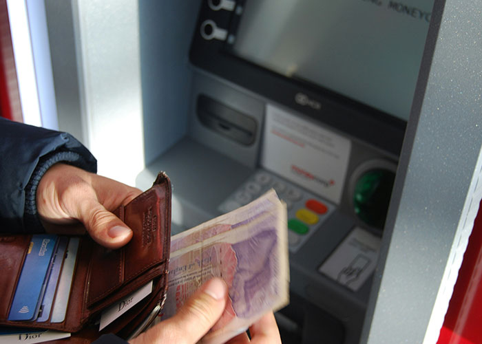 Person holding cash near an ATM, symbolizing workplace toxicity and quitting without warning.