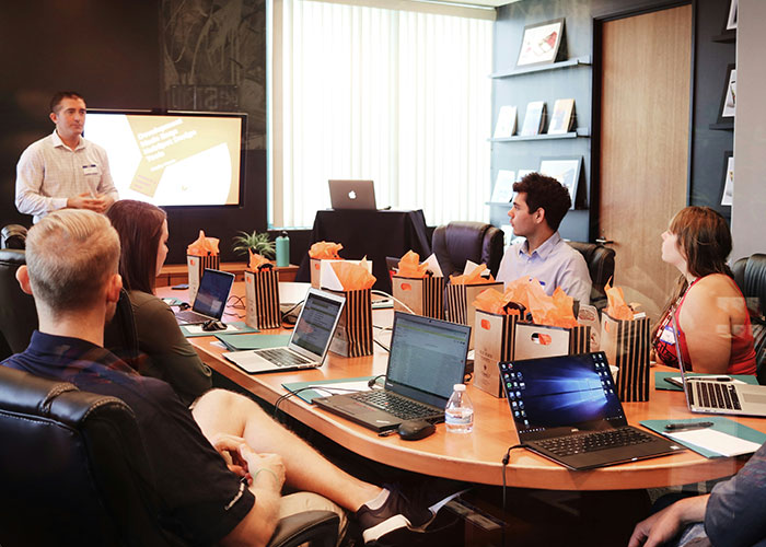 Team meeting in a conference room with laptops and presentation, discussing a toxic workplace environment.