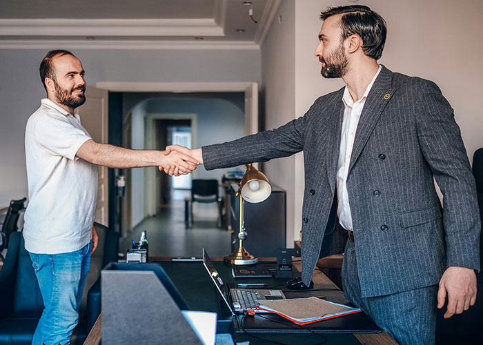 Two men shaking hands in an office setting, representing a toxic workplace environment.