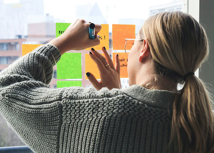 Person writing on colorful sticky notes on window, reflecting a toxic workplace environment.