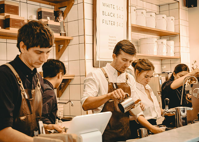 Baristas working in a busy coffee shop, displaying signs of workplace stress.