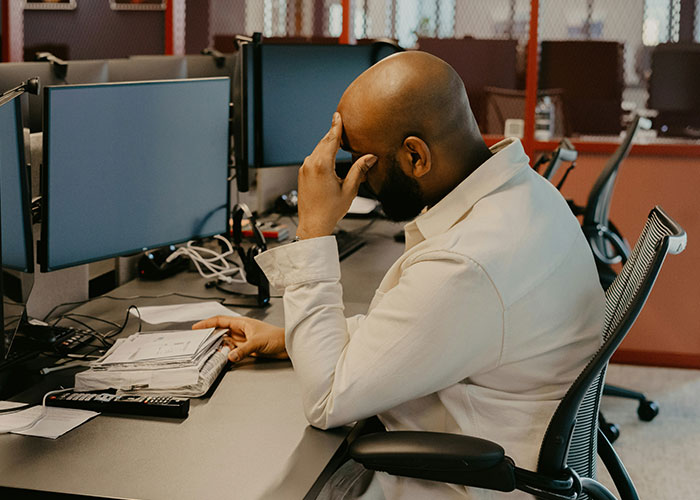 Man stressed at desk, highlighting toxic workplace impact.