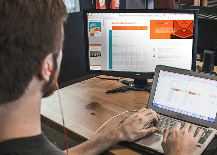 Person working at a desk with two screens, highlighting a potentially toxic workplace environment.