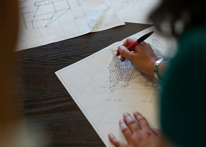 Person working on architectural drawings at a desk, illustrating a toxic workplace environment.