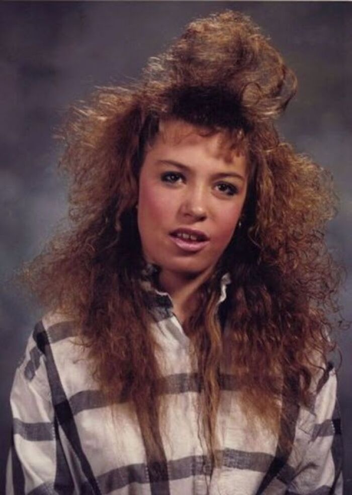 Woman with high, wild 1980s hair and a plaid shirt, showcasing an epic hair disaster.