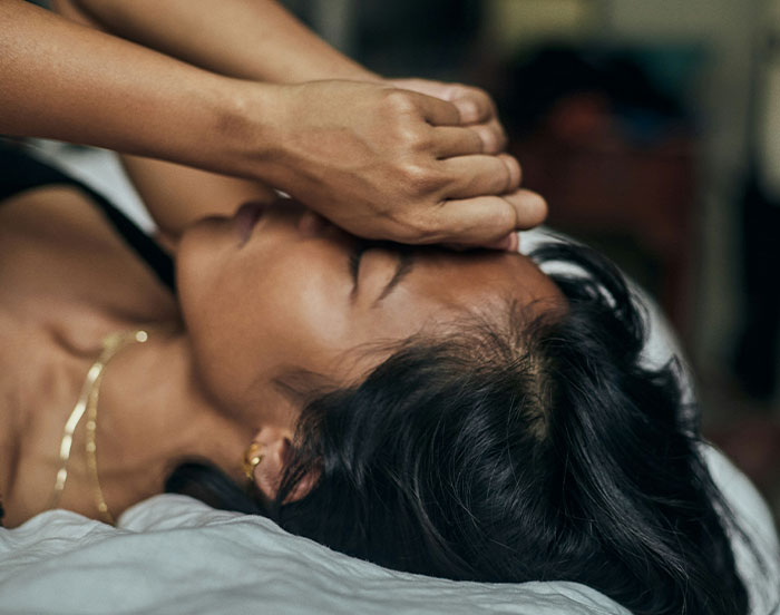 Person lying on bed, covering face, illustrating unhinged emotions for attention.