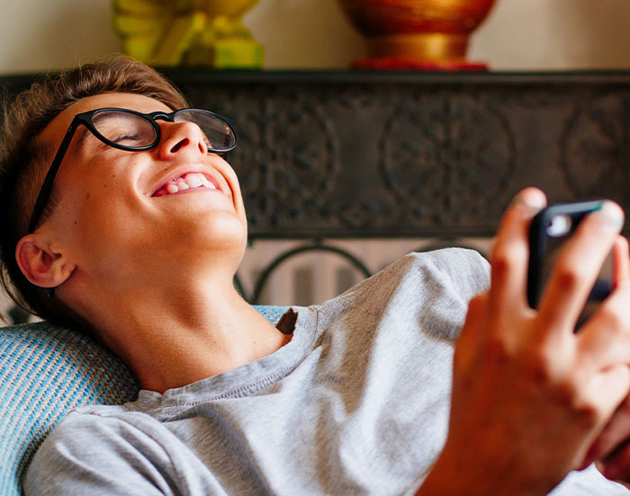 Person smiling and looking up, holding a smartphone, seeking attention online.